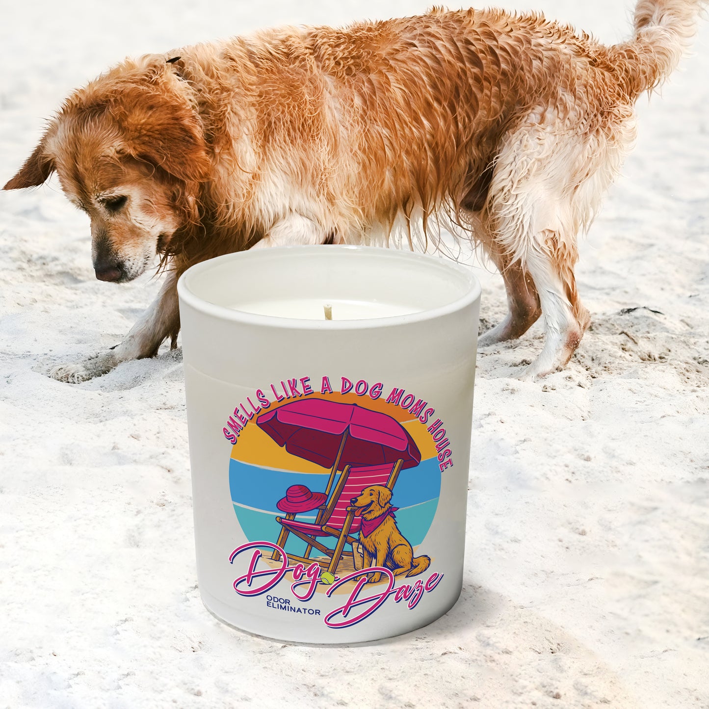 Candle with a dog-themed design on a sandy surface with a dog in the background digging a hole at the beach